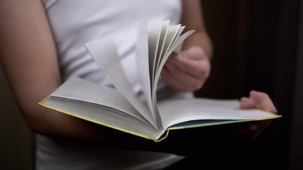 閉じます 本のページを通して認識できない少年フリッピング 手に本を保持立って すぐに部屋の遅い動きでページをめくる 読書だ 背景がぼやけている 概念教育 — ストック動画