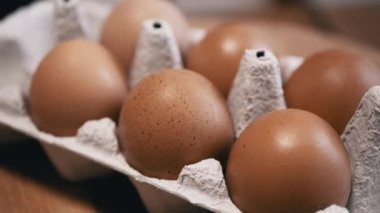 Yaklaş, Tahta bir arka planda karton tepside taze tavuk yumurtası. Makro. Yumurta tepsisinde, kahverengi kabuklu çiğ yumurta. Doku. Seçici odaklanma. Üst Manzara. Görüldü. Işık. Organik ürün.