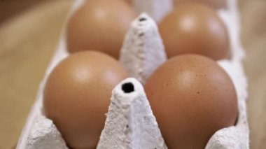 Yaklaş, Tahta bir arka planda karton tepside taze tavuk yumurtası. Makro. Yumurta tepsisinde, kahverengi kabuklu çiğ yumurta. Doku. Seçici odaklanma. Üst Manzara. Görüldü. Işık. Organik ürün.
