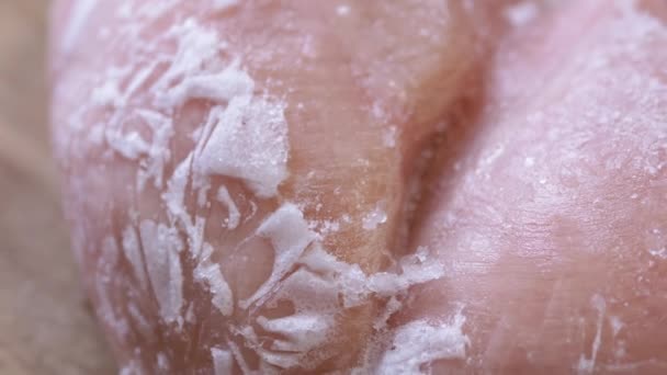 回転する背景に氷の地殻で覆われた冷凍肉の大片 閉めろ 氷の雪 氷の地殻と冷凍鶏の切り身 テクスチャ 食料が破壊される 隔離されてる 選択的フォーカス — ストック動画