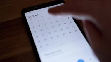 Kız, Smartphone Screen 'de Elektronik Takvim Uygulamasına Yeni Bir Olay Ekliyor. Tarih ve ayı ararken sayfayı elden ele gezdiriyor. ABD 'nin Bağımsızlık Günü cep telefonu uygulamasına ekleniyor. Kapat..