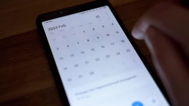 女性手指是滚动日历应用程序在手机屏幕上寻找日期 靠近点2023年 智能手机中的电子日历 孤立无援滑行运动 — 图库视频影像