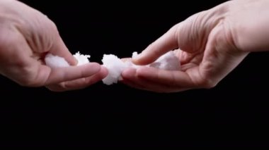 Yakından bakınca, Ellerinde Eriyen Islak Kar Siyah Arkaplanda Tutan Kadın. Kar kristalleri, buz erir ve etrafa dağılır. Patlama oldu. İzole edilmiş arka plan. Bir parçası. Eller yukarı. Tanımlanamayan kişi. Kış.