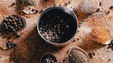 Yakın plan, Hint Baharatlı Kaşıklar Renkli Tahta Arkaplanda Dönüyor. Ağır çekim. Dağıtılmış baharat karışımı, karabiber, zerdeçal, paprika, kişniş, kekik. Arkaplan, doku.