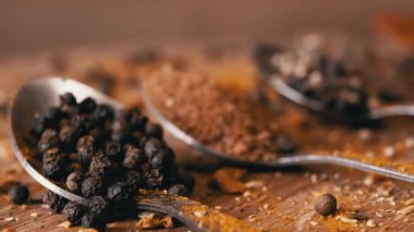 Yakın plan, Hint Baharatlı Kaşıklar Renkli Tahta Arkaplanda Dönüyor. Ağır çekim. Dağıtılmış baharat karışımı, karabiber, zerdeçal, paprika, kişniş, kekik. Arkaplan, doku.