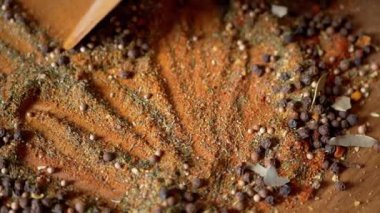 Renkli Dönen Arkaplan 'da Tahta Spatula ile karıştırılmış Hint Baharatları. Kapatın. Baharatlı biberler, kurutulmuş otlar, dereotu, paprika, zerdeçal, kekik. Doku, şekil. Palet kurutulmuş baharat..