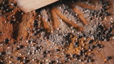 Renkli Dönen Arkaplan 'da Tahta Spatula ile karıştırılmış Hint Baharatları. Kapatın. Baharatlı biberler, kurutulmuş otlar, dereotu, paprika, zerdeçal, kekik. Doku, şekil. Palet kurutulmuş baharat..