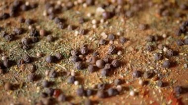 Renkli Baharatların Dönen Ahşap Arkaplanda Kurutulmuş Baharatlar Şelalesi. Kapatın. Ağır çekim. Dağınık Hint baharatı karışımı, siyah biber, zerdeçal, paprika, kişniş, kekik. Arkaplan, doku.