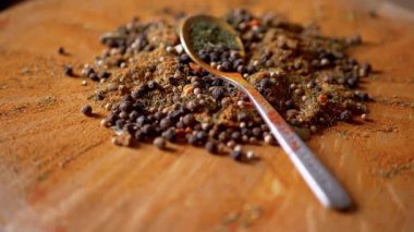 Renkli ahşap bir arka planda Hint Baharatları Rotasyonu ile kaşık. Kapatın. Ağır çekim. Yığın. Baharat karışımı, karabiber, zerdeçal, paprika, kişniş, kekik. Arkaplan ve doku.