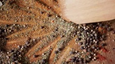 Renkli Dönen Arkaplan 'da Tahta Spatula ile karıştırılmış Hint Baharatları. Kapatın. Baharatlı biberler, kurutulmuş otlar, dereotu, paprika, zerdeçal, kekik. Doku, şekil. Palet kurutulmuş baharat..