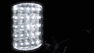 Parlayan El fenerinin Siyah Arkaplanında Bir Duman Bulutu Yükseliyor. Duman dokusu. Enerji krizi kavramı, bilinç kaybı, enerji tasarrufu. Soyut. Ampullü spot ışığı. Bulanık arkaplan.