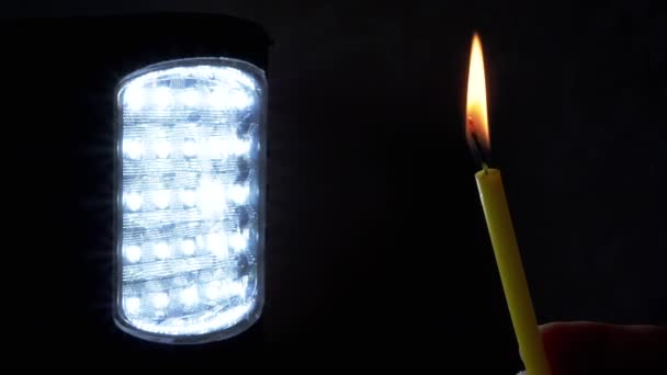 手握着一个在黑色背景上有开关闪光灯的燃烧的蜡烛 靠近点复制空间 能源危机的概念 节省家里的电 乌克兰战争 停电的情况 — 图库视频影像