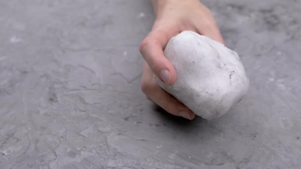靠近点 一个女人手里拿着一个肮脏的雪球在灰色的混凝土背景上 孤立的背景 身体的一部分 无法辨认的人冰球冬季概念 — 图库视频影像
