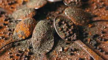 Yakın plan, Hint Baharatlı Kaşıklar Renkli Tahta Arkaplanda Dönüyor. Ağır çekim. Dağıtılmış baharat karışımı, karabiber, zerdeçal, paprika, kişniş, kekik. Arkaplan, doku.
