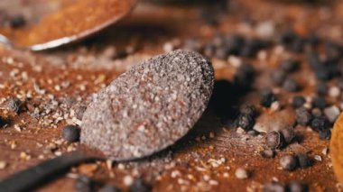 Yakın plan, Hint Baharatlı Kaşıklar Renkli Tahta Arkaplanda Dönüyor. Ağır çekim. Dağıtılmış baharat karışımı, karabiber, zerdeçal, paprika, kişniş, kekik. Arkaplan, doku.