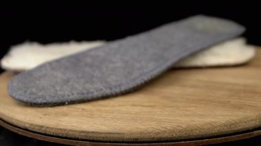 Yakın çekim, Sıcak Yün Ayakkabı Tabanları Tahta Tahta üzerinde, Siyah Arkaplan 'da dönüyor. Yan görüş. İki tane. Bulanık hareket. Seçici odaklanma. Daire daire dönüyor. Uzayı kopyala İzole edilmiş. Kış zamanı. Ortopedik.