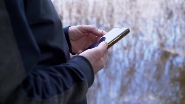 Ruce Muže Napsat Zprávu Smartphone Poblíž River Bank Nature Nerozpoznatelná — Stock video