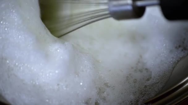 閉じる ウィスクとミキサーは ふわふわの白い泡に生の卵の白をホイップ スローモーション テクスチャ 砂糖でタンパク質クリームを作るプロセス 家庭用キッチンでメレンゲ — ストック動画