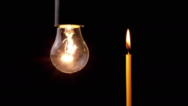 閉じる バーニングキャンドルの黒の背景に暗い部屋でフリッカーランプ 暖かい光をオンにしたタングステン白熱電球 エネルギー危機 電気だ 停電だ 停電だ — ストック動画