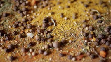 Renkli Baharatların Dönen Ahşap Arkaplanda Kurutulmuş Baharatlar Şelalesi. Kapatın. Ağır çekim. Dağınık Hint baharatı karışımı, siyah biber, zerdeçal, paprika, kişniş, kekik. Arkaplan, doku.