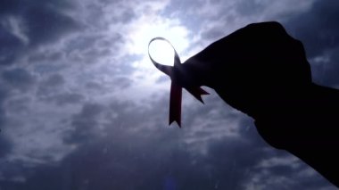 Kadın Ellerinin Silueti Gri Bulutların Arkasında Pembe Kurdele Gösteriyor. Göğüs kanseri sembolü olan bir el penceredeki kümülüs bulutlarının arasından güneş ışığına ulaşır. Ekim ayı.