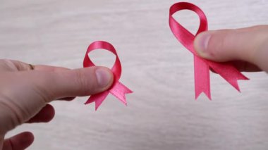 Kadın Elleri Ahşap Beyaz Arkaplanda İki Pembe Kurdele Gösteriyor. Kapatın. Göğüs kanseri sembollü bir el. Kanser bilgisi. Umut. Ekim ayı. Uluslararası AIDS, Kanser Günü. Hastalık Bilinci.