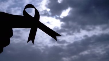 Kadın Ellerinin Silueti Gri Bulutların Arkasında Pembe Kurdele Gösteriyor. Göğüs kanseri sembolü olan bir el penceredeki kümülüs bulutlarının arasından güneş ışığına ulaşır. Ekim ayı.