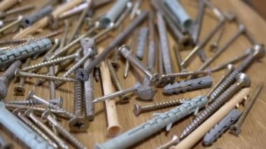 Bir sürü Paslanmaz Çelik Fastener döner ahşap arka planda. Kapatın. Bir sürü galvanize edilmiş, kendi kendine dokunabilen vida plastik perdeler, vidalar, cıvatalar ve çamaşır makineleri. Seçici odak.