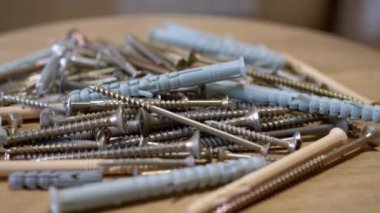 Bir sürü Paslanmaz Çelik Fastener döner ahşap arka planda. Kapatın. Bir sürü galvanize edilmiş, kendi kendine dokunabilen vida plastik perdeler, vidalar, cıvatalar ve çamaşır makineleri. Seçici odak.