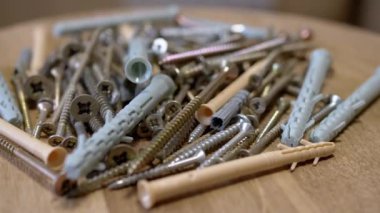 Bir sürü Paslanmaz Çelik Fastener döner ahşap arka planda. Kapatın. Bir sürü galvanize edilmiş, kendi kendine dokunabilen vida plastik perdeler, vidalar, cıvatalar ve çamaşır makineleri. Seçici odak.