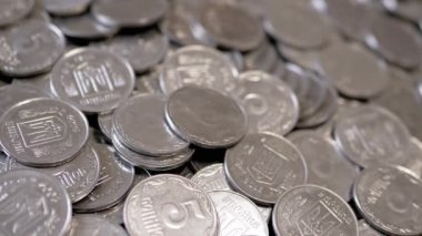 Yakın plan, Dönen Arkaplanda Bir sürü gümüş sikke. Para geçmişi. Ukrayna kuruşları, kopekler. Hareket ediyor, dönüyor. Finansal kriz, birikim, birikim. Ukrayna amblemi, damga.