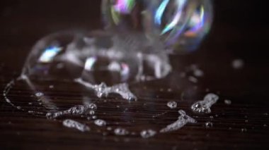 Yakından bakınca, bir sürü renkli sabun köpüğü kahverengi tahta bir yüzeye yapışmış. Şeffaf gökkuşağı kabarcıkları köpüklü sinek, bağlantı, patlama. Kabarcık sürüsü. Su sıçrattı. Doku, yapı. Görüntü. Soyut.