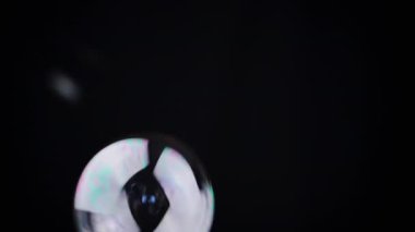 Renkli sabun köpükleri izole edilmiş siyah arka planda boş bir alanda uçuyor. Birçok gökkuşağı şeffaf kabarcıkları rastgele döner, yüzer, düşer. Bulanık hareket. Seçici odaklanma. Soyut. Oyun bitti. Yavaş çekim.