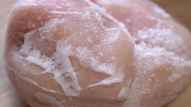 在旋转的背景上用冰块覆盖了一大块冻肉 靠近点结冰的鸡肉片和结冰的雪皮 食物解冻了 孤立无援选择性焦点 — 图库视频影像