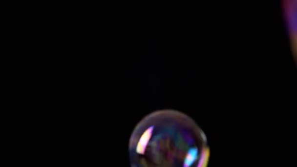彩色的肥皂泡在一个空旷的空间中 在孤立的黑色背景下飞舞 三个巨大的彩虹气泡旋转 模糊的动议 有选择的重点 慢动作游戏 接近了 — 图库视频影像