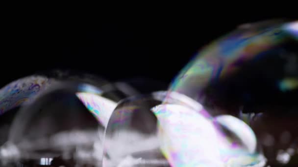近距离观察 在木制表面上有很多彩色的肥皂泡在一起 透明的彩虹气泡 泡沫飞舞 泡泡束 模糊的动议 黑色背景 — 图库视频影像
