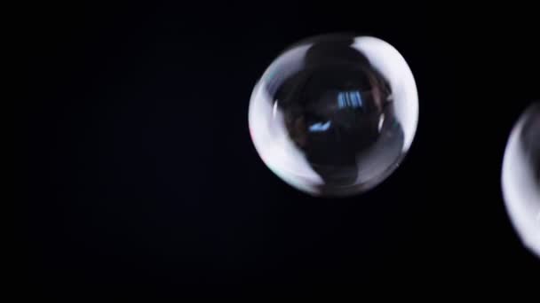 彩色的肥皂泡在一个空旷的空间中 在孤立的黑色背景下飞舞 许多大的 小的彩虹气泡随机旋转 模糊的动议 有选择的重点 慢动作游戏 — 图库视频影像