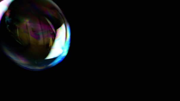 近距离观察 一个色彩斑斓的肥皂泡在黑色背景上缓缓飘扬 透明彩虹气泡在空旷的空间 模糊的动议 集中精神纹理 慢动作 — 图库视频影像