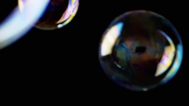 カラフルな石鹸の泡は 隔離された黒の背景に空の空間に飛びます 多くの大規模な 小さな虹の泡がランダムに回転し フロート バースト 燃えるような動き 集中しろ 抽象的 スローモーション — ストック動画