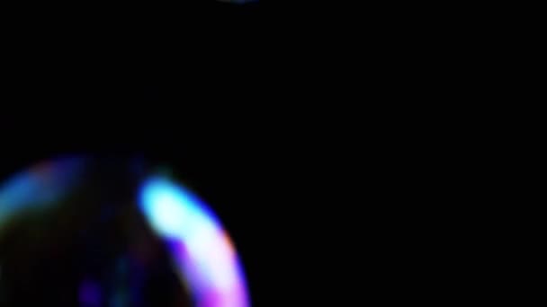 カラフルな石鹸の泡は 隔離された黒の背景に空の空間に飛びます 多くの大規模な 小さな虹の泡がランダムに回転し フロート 燃えるような動き 選択的フォーカス 抽象的 スローモーション ゲーム — ストック動画