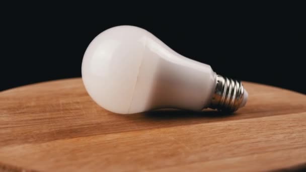 Одна Энергосберегающая Лампочка Крутящаяся Вуденской Доске Черный Фон Круглая Белая — стоковое видео
