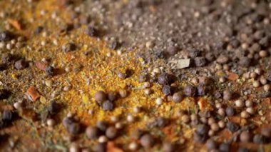 Renkli Baharatların Dönen Ahşap Arkaplanda Kurutulmuş Baharatlar Şelalesi. Kapatın. Ağır çekim. Dağınık Hint baharatı karışımı, siyah biber, zerdeçal, paprika, kişniş, kekik. Arkaplan, doku.