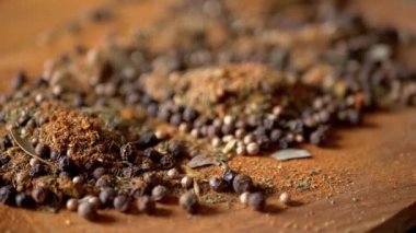 Değişen ahşap arka planda çeşitli çok renkli Hint baharatları serpiştirilmiş. Parlak aromatik kuru baharatların bileşimi. Baharatlı biberler, kurutulmuş bitkiler, dereotu, paprika, zerdeçal, kekik.