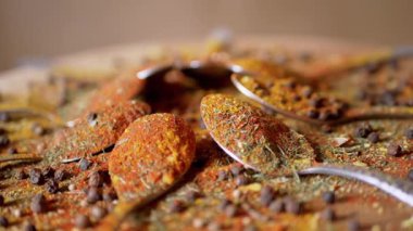 Hint baharatlı kaşıklar renkli ahşap arka planda döner. Kapatın. Ağır çekim. Dağıtılmış baharat karışımı, karabiber, zerdeçal, paprika, kişniş, kekik. Arkaplan, doku.