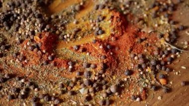 Değişen ahşap arka planda çeşitli çok renkli Hint baharatları serpiştirilmiş. Parlak aromatik kuru baharatların bileşimi. Baharatlı biberler, kurutulmuş bitkiler, dereotu, paprika, zerdeçal, kekik.