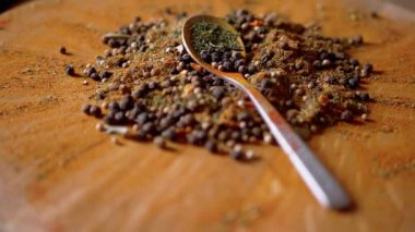 Renkli ahşap bir arka planda Hint Baharatları Rotasyonu ile kaşık. Kapatın. Ağır çekim. Yığın. Baharat karışımı, karabiber, zerdeçal, paprika, kişniş, kekik. Arkaplan ve doku.