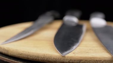Yaklaş, Bıçak Takımı Kara Arkaplanda Tahta Turntable 'da Dönüyor. Çelik mutfak bıçaklarından keskin bıçaklar. Şef için profesyonel bıçaklar. Çatal bıçak. Ahşap arka plan, bulanık. Yemek pişirme konsepti.