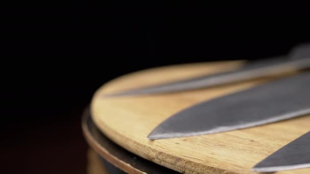 近距离观察 一组刀具在黑色背景的木制转盘上旋转 锋利的钢制厨房刀片 厨师用的专业刀餐具 木制背景 烹调概念 — 图库视频影像