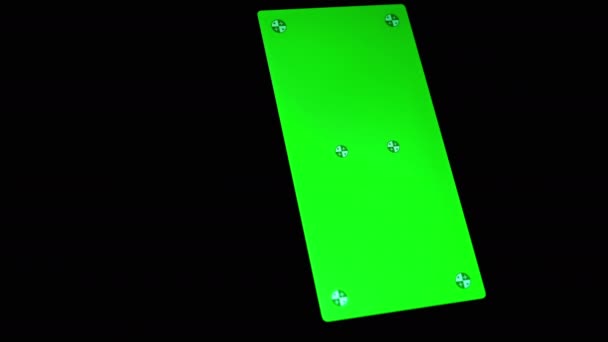緑色のスクリーンが付いているスマートフォンは暗い部屋の黒い背景で回ります 空きスペース テキストのための場所 マーカーズ ガジェット 輝くスクリーンが付いている携帯電話 クロムカヤックの背景 クローズアップ — ストック動画