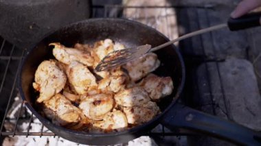 Doğa 'da Kızartma Tavasında Etli Izgara Pişiriyorum. Eti bir spatulayla karıştırır. Dışarıda yanan bir ateşin üstünde yemek, odun, duman. Konsept kamp, turizm, gezi. Barbekü ızgarası.